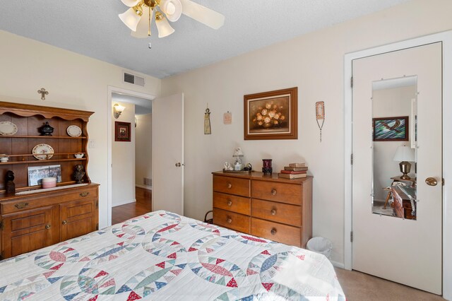 carpeted bedroom featuring ceiling fan, a textured ceiling, and visible vents