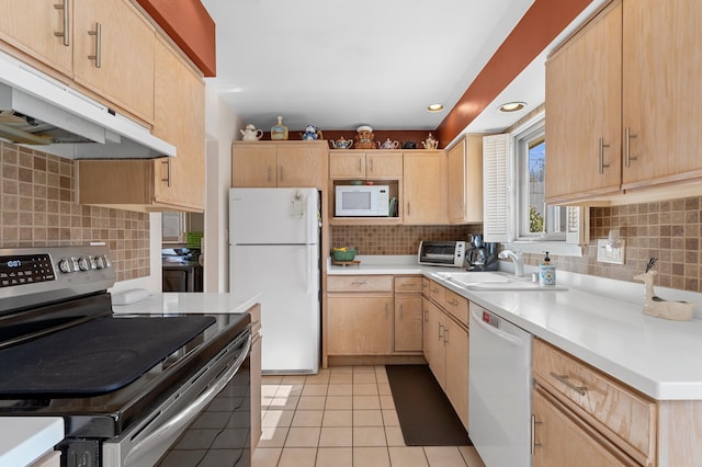 kitchen with white appliances, light brown cabinets, under cabinet range hood, and a sink