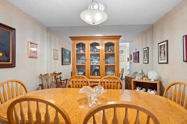 dining space with a textured ceiling and wallpapered walls