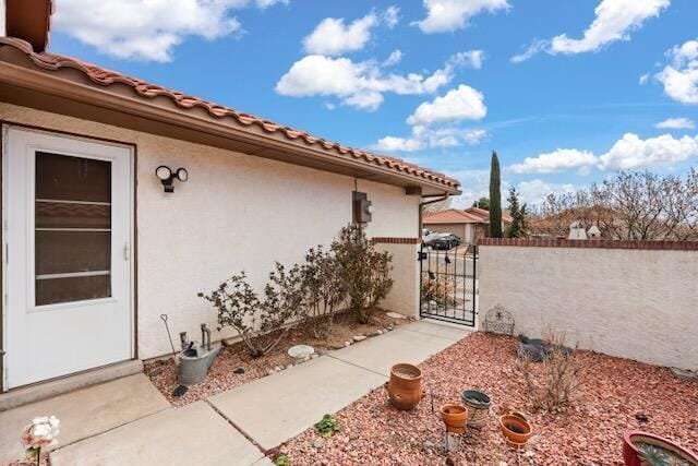 view of home's exterior with stucco siding, fence, and a gate