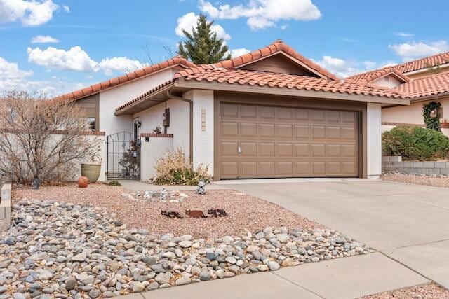 view of front of property with stucco siding, an attached garage, driveway, and a gate