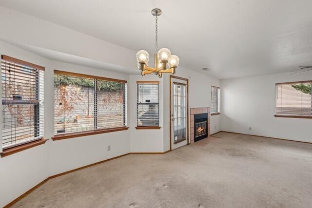 unfurnished living room with baseboards, carpet floors, a notable chandelier, and a tiled fireplace