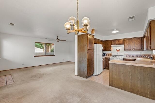 kitchen featuring visible vents, open floor plan, ceiling fan with notable chandelier, white appliances, and a sink