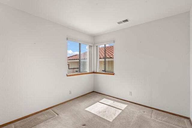 carpeted empty room featuring baseboards and visible vents