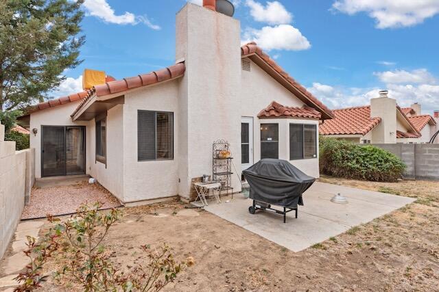 back of property with stucco siding, a tiled roof, fence, a chimney, and a patio area