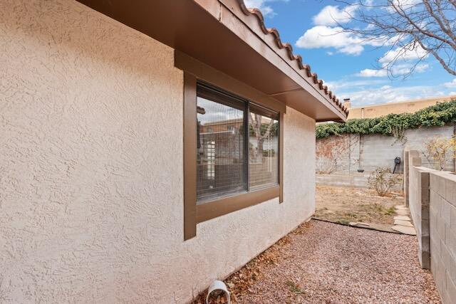 view of side of home featuring stucco siding and fence