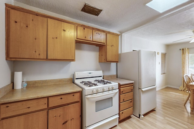 kitchen featuring white appliances, a textured ceiling, light wood finished floors, and light countertops