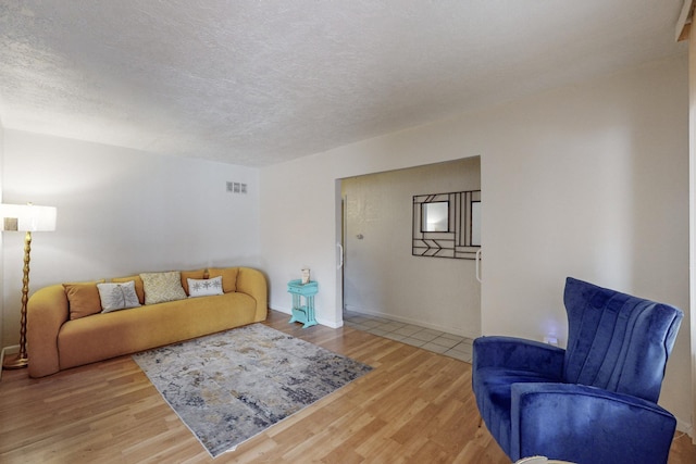 living room with a textured ceiling, wood finished floors, and visible vents