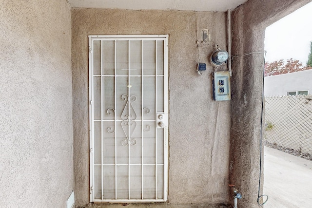 doorway to property featuring fence and stucco siding