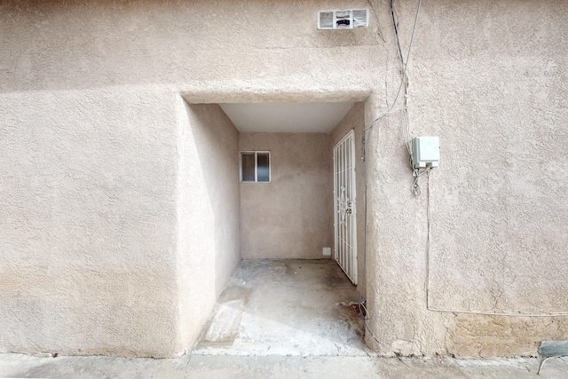 entrance to property with visible vents and stucco siding