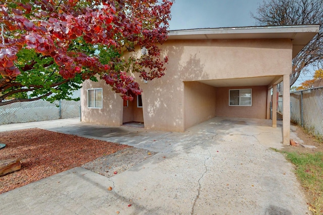 view of front of home featuring a fenced backyard, driveway, a patio, and stucco siding