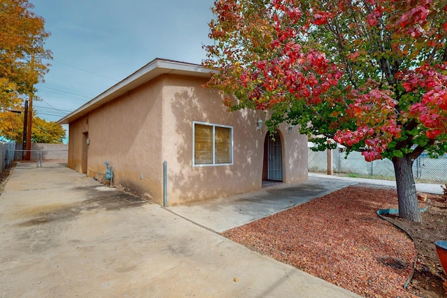 view of side of property featuring fence, a patio, and stucco siding