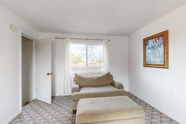 sitting room featuring light carpet, baseboards, and a textured ceiling