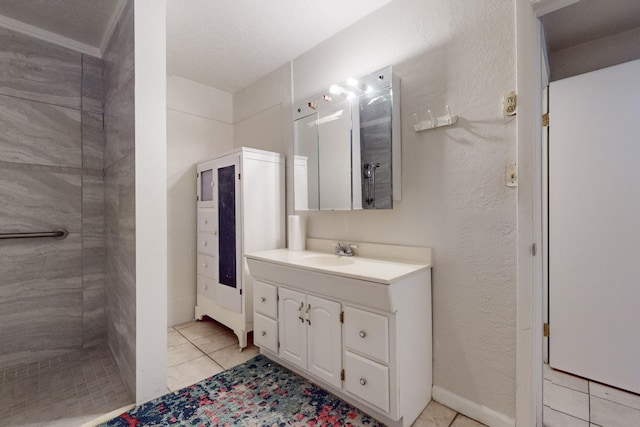 bathroom with tiled shower, a textured wall, vanity, and tile patterned floors