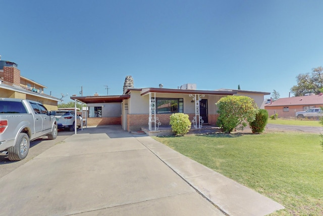 view of front facade with brick siding, a porch, an attached carport, driveway, and a front lawn