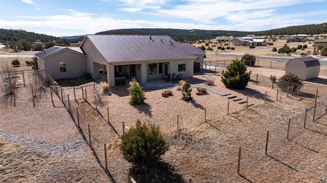 rear view of property with a storage shed, a patio, a fenced backyard, metal roof, and an outdoor structure