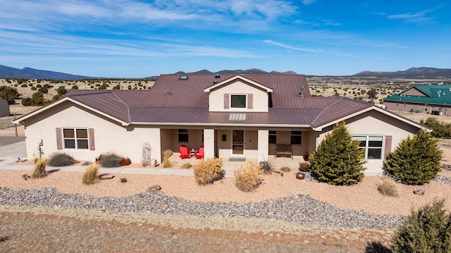 view of front of house with a porch, metal roof, a mountain view, and stucco siding