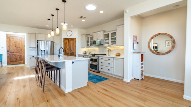 kitchen with stainless steel appliances, a breakfast bar, a sink, visible vents, and light countertops