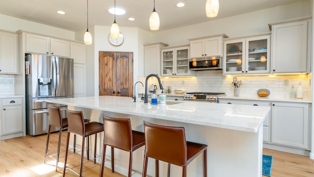 kitchen featuring stainless steel appliances, light wood-type flooring, a sink, and a kitchen bar