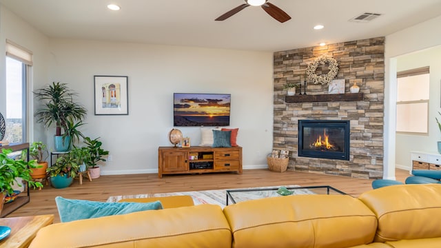 living room featuring recessed lighting, visible vents, wood finished floors, and a stone fireplace