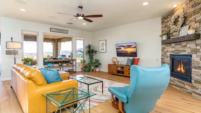 living room with recessed lighting, a stone fireplace, baseboards, and wood finished floors