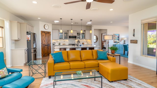 living area featuring light wood-type flooring, baseboards, and recessed lighting