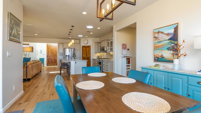 dining room featuring baseboards, recessed lighting, and light wood-style floors