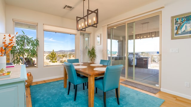 dining area featuring a healthy amount of sunlight, baseboards, visible vents, and wood finished floors