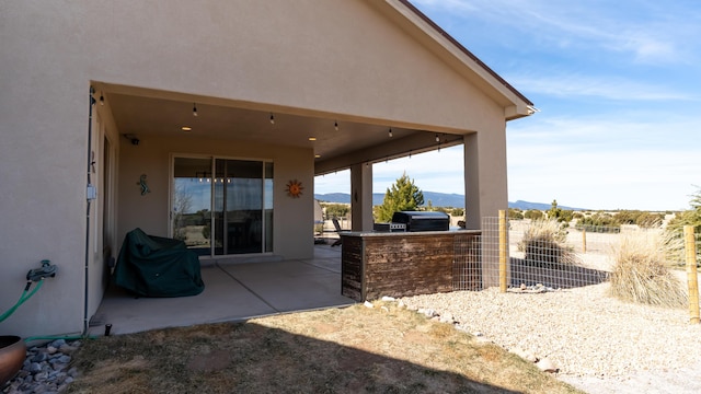 view of patio / terrace with grilling area, an outdoor kitchen, fence, and a mountain view