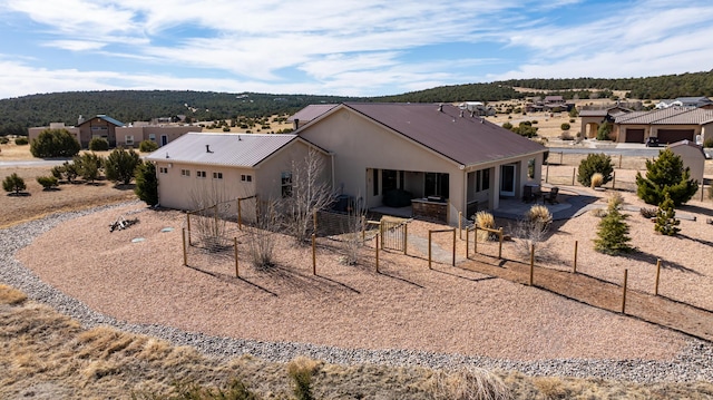 view of front facade with metal roof, a patio area, fence, and stucco siding