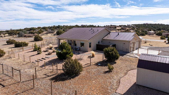 exterior space with metal roof, an attached garage, fence, concrete driveway, and a patio area