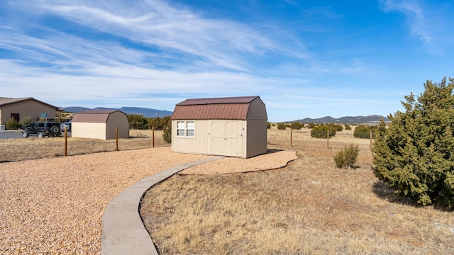 view of yard featuring a shed, a mountain view, and an outdoor structure