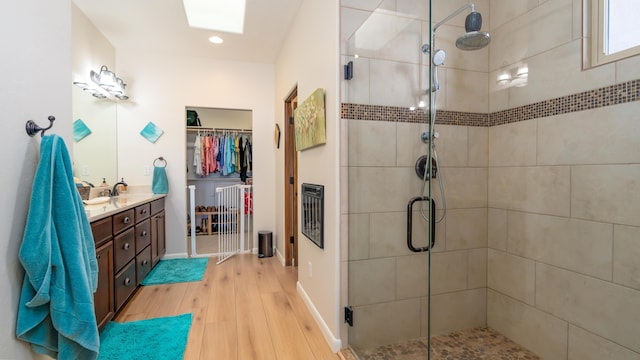 bathroom featuring a stall shower, baseboards, wood finished floors, a walk in closet, and vanity