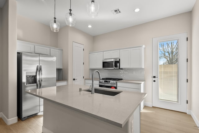 kitchen featuring stainless steel appliances, a sink, visible vents, light wood-type flooring, and tasteful backsplash