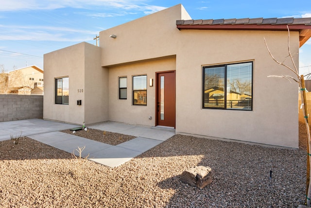 rear view of house featuring a patio area, fence, and stucco siding