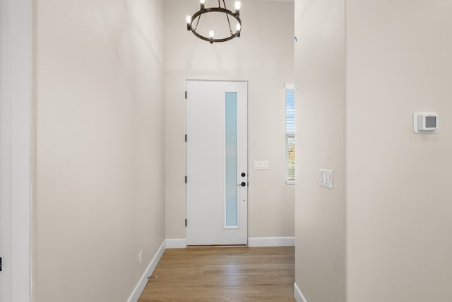 foyer entrance with a chandelier, light wood-type flooring, and baseboards