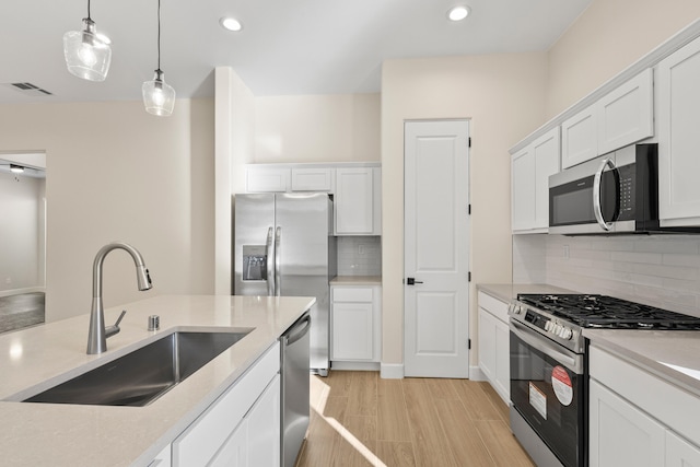 kitchen featuring a sink, visible vents, white cabinetry, hanging light fixtures, and appliances with stainless steel finishes