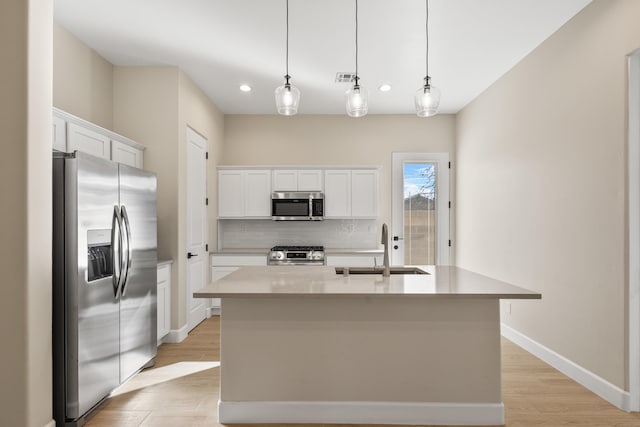 kitchen with light wood-style flooring, a sink, white cabinets, appliances with stainless steel finishes, and backsplash