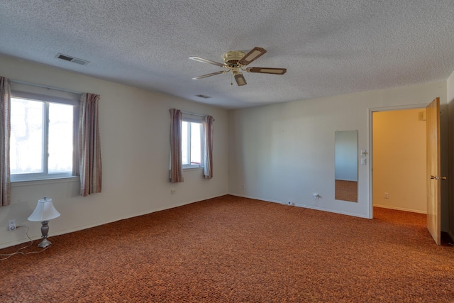 carpeted empty room featuring a ceiling fan, visible vents, and a textured ceiling