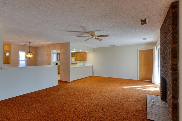 unfurnished living room featuring carpet floors, visible vents, a fireplace, and ceiling fan