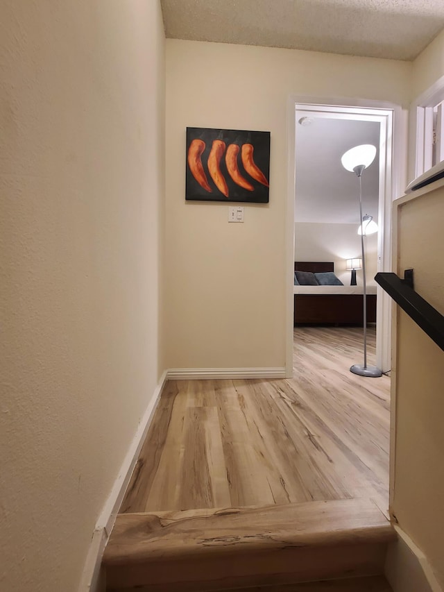 corridor with baseboards and wood finished floors