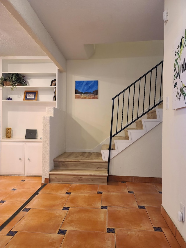 stairway featuring built in shelves, tile patterned flooring, and baseboards