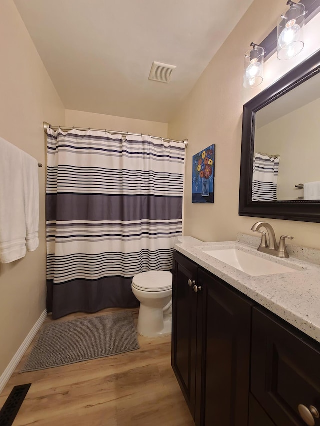 bathroom with visible vents, toilet, vanity, wood finished floors, and baseboards