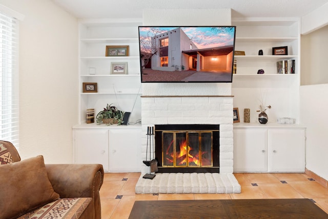 living area with a brick fireplace, built in features, and light tile patterned flooring