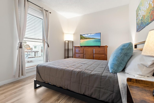 bedroom featuring a textured ceiling, baseboards, and wood finished floors