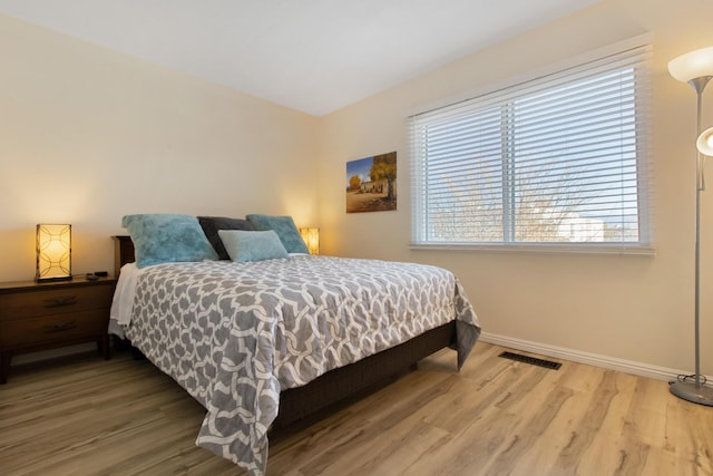 bedroom featuring visible vents, baseboards, and wood finished floors