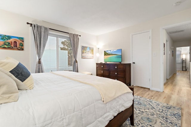 bedroom with light wood-style flooring, visible vents, and baseboards