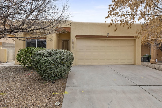 pueblo-style house featuring concrete driveway and stucco siding