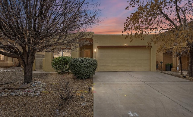 southwest-style home with a garage, driveway, and stucco siding