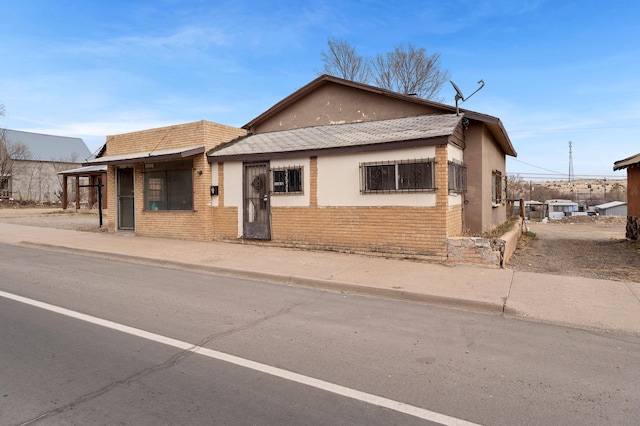 view of front of property featuring brick siding and stucco siding